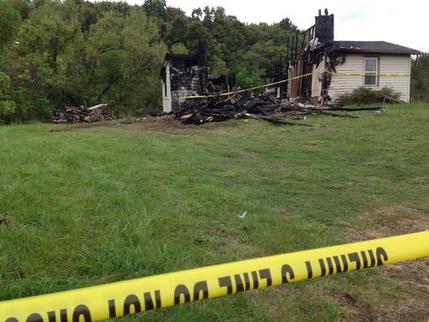 Police tape cordons off the remains of a house. Wednesday Sept. 14 2016 in rural Richland County near Mansfield Ohio where authorities say a woman's body was found nearby. Police say a suspect in the abduction of a woman in neighboring Ashland