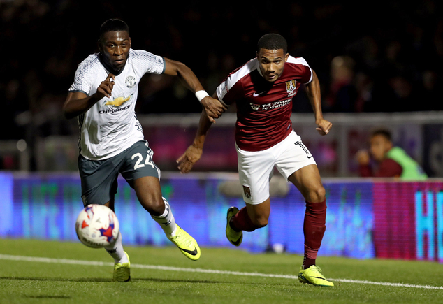 Northampton Town's Kenji Gorre right and Manchester United's Timothy Fosu Mensah run towards the ball during the English League Cup third round soccer matc