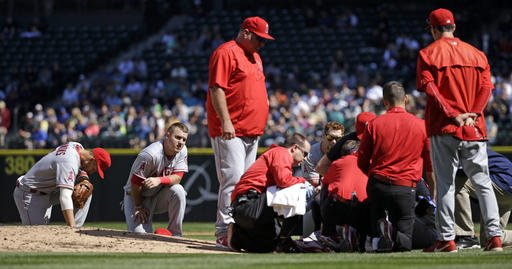 Los Angeles Angels infielders Andrelton Simmons left and Mike Trout kneel nearby as starting pitcher Matt Shoemaker is treated at right after being hit by a line drive from Seattle Mariners Kyle Seager in the second inning of a baseball game Sunday S