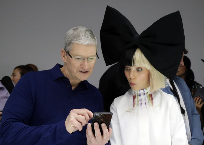 Apple CEO Tim Cook shows an iPhone 7 to performer Maddie Ziegler during an event to announce new products Wednesday Sept. 7 2016 in San Francisco