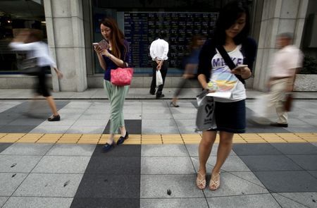 A pedestrian looks at an electronic board showing the various stock prices outside a brokerage in Tokyo