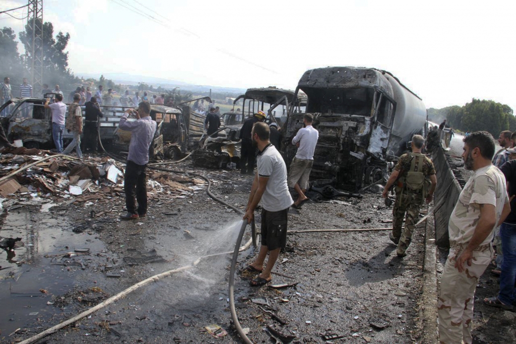 Syrian official news agency SANA Syrian security forces emergency services and residents look at the remains of burned vehicles at the site of a bombing in Tartus Syria on Sept. 5 2016