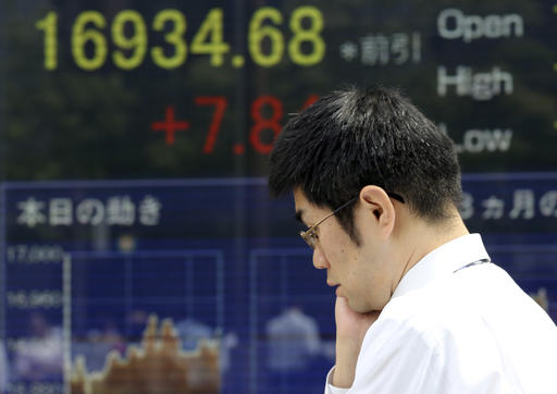 A man walks by an electronic stock board of a securities firm in Tokyo Friday Sept. 2 2016. Most Asian markets were listless Friday as investors awaited key U.S. job data that could influence the Fed's interest rate policy