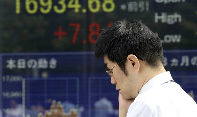 A man walks by an electronic stock board of a securities firm in Tokyo Friday Sept. 2 2016. Most Asian markets were listless Friday as investors awaited key U.S. job data that could influence the Fed's interest rate policy. (AP