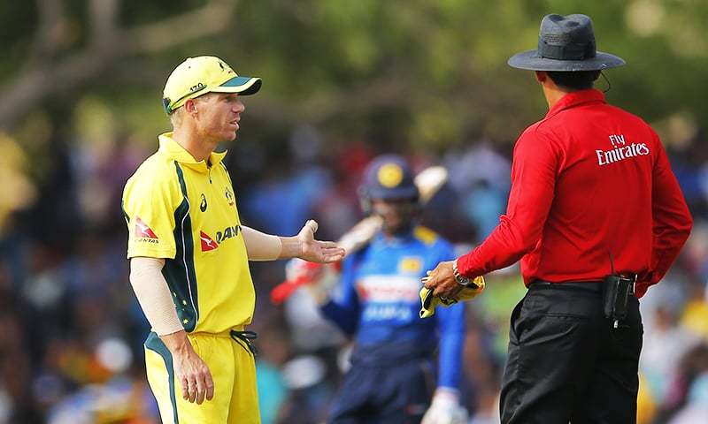 Australia's standing in captain David Warner left chats with umpire Ruchira Palliyaguru during their fourth ODI against Sri Lanka in Dambulla. — AP