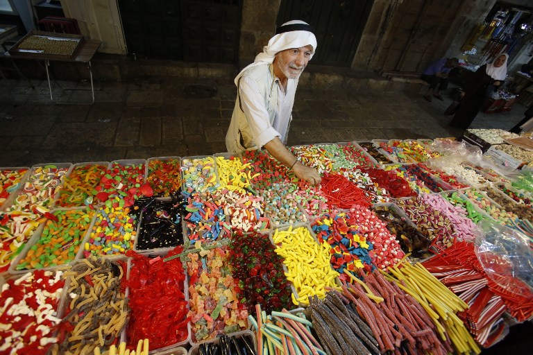 A Palestinian man buys sweets as Muslims shop in preparation for the holiday of Eid al Adha at the market in the Old City of Jerusalem