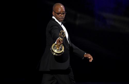 Courtney B. Vance holding golden award statue in black tuxedo with white shirt against black background