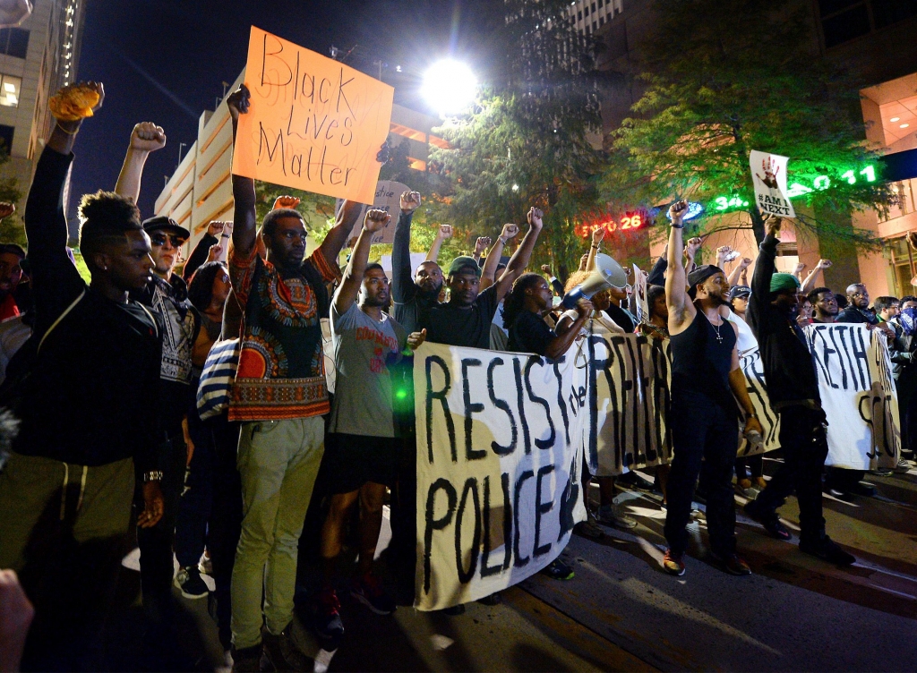 Protesters stand in unity as they prepare to march throughout the city to protest Tuesday's fatal police shooting of Keith Lamont Scott in Charlotte N.C. Friday Sept. 23 2016