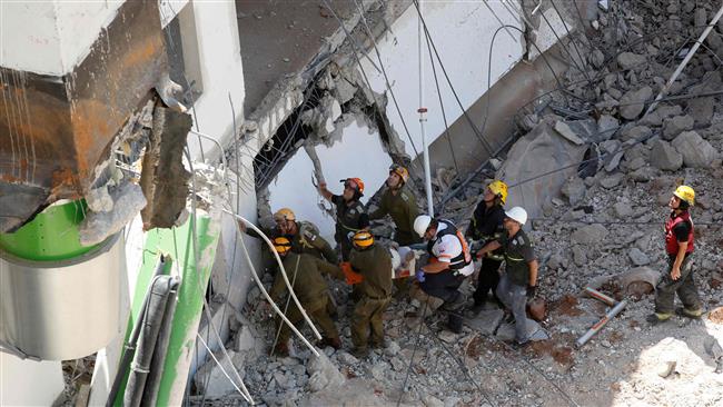 Israeli medics and emergency units carry a wounded person away on a stretcher from a construction site after an underground car park collapsed