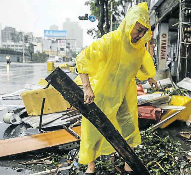 CLEARING UP A resident sifts through debris after strong winds and rain from typhoon Meranti hit southern Taiwan yesterday