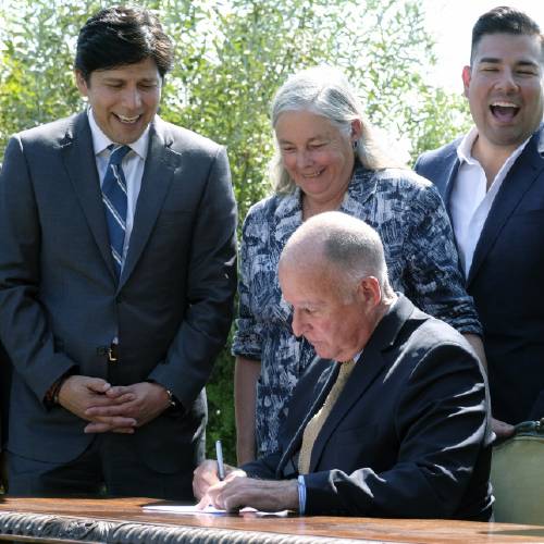 Jerry Brown seated signs legislation while joined by Senate President pro tempore Kevin de Leon D Los Angeles second from left and state Sen. Fran Pavley D Agoura Hills Thursday Sept. 8 2016 in Los Angeles. The law sets