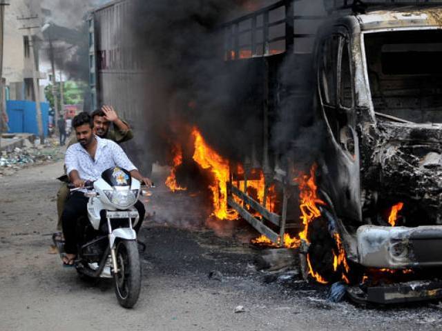 Men ride a motorcycle past a lorry in Bengaluru which was set on fire by protesters after India's Supreme Court ordered Karnataka state to release 12,000 cubic feet of water per second every day from the Cauvery river to neighbouring Tamil Nadu Ind