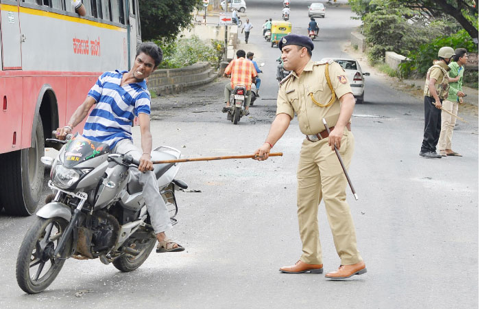 A police personnel canes a motorcyclist during a curfew following violence in the city due to the Cauvery water sharing dispute with neighboring state Tamil Nadu in Bangalore on Tuesday. — AFP