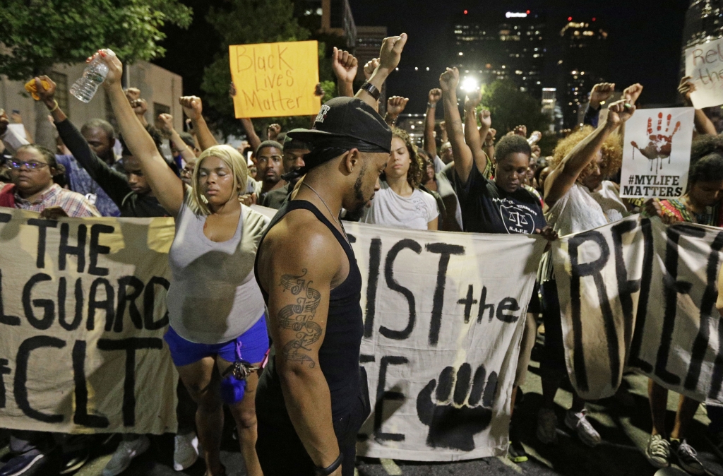 Protesters raises their fists as they observer a moment of silence as they march in the streets of Charlotte N.C. Friday Sept. 23 2016 over Tuesday's fatal police shooting of Keith Lamont Scott