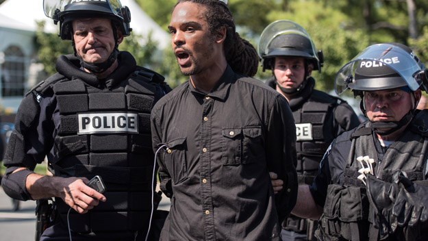 Police in riot gear detain a demonstrator outside of Bank of America Stadium before an NFL football game between the Charlotte Panthers and the Minnesota Vikings