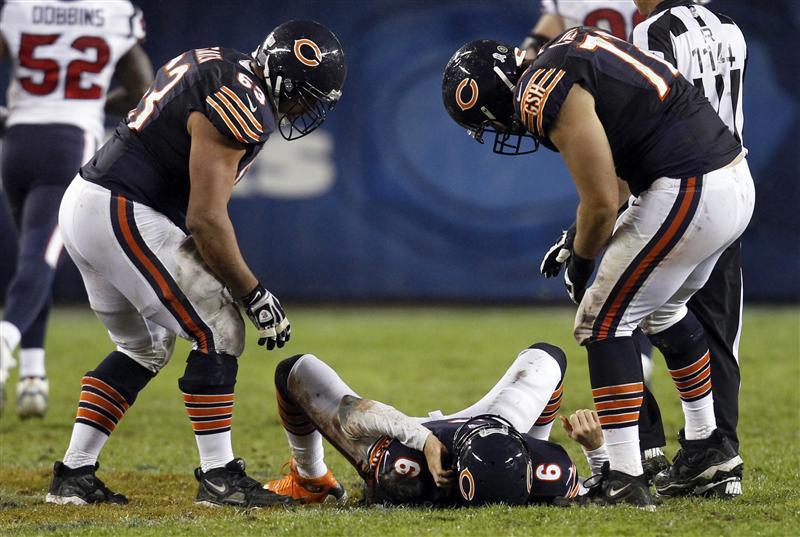 Chicago Bears quarterback Jay Cutler lies on the field after being hit late on a play by the Houston Texans with his teammates over him