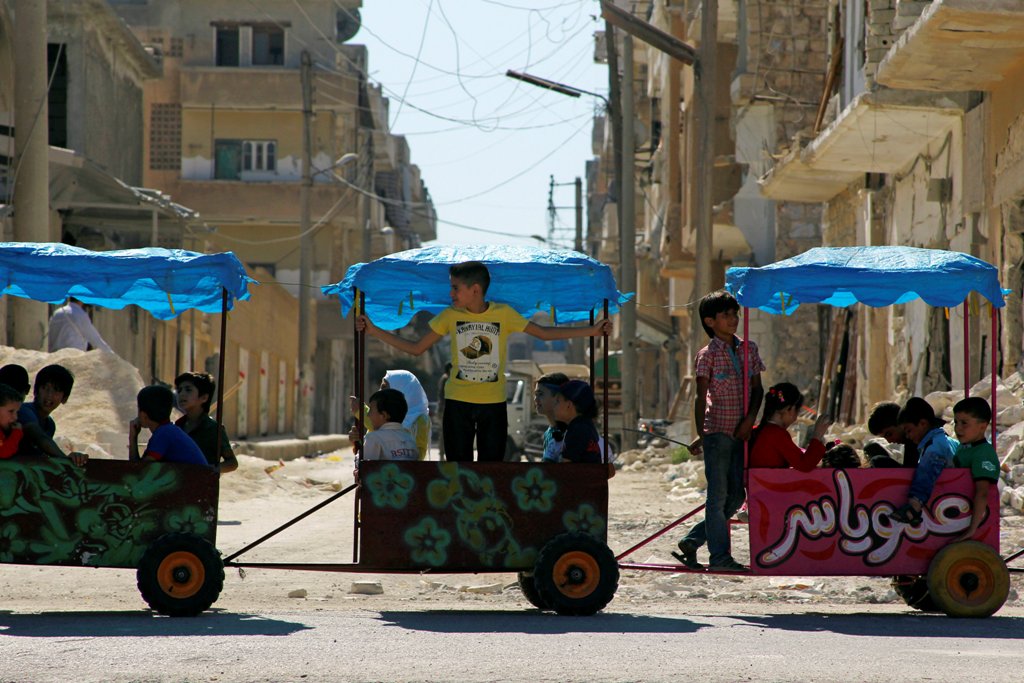 Children ride in carts on the third day of Eid al Adha in the rebel controlled city of Idlib Syria