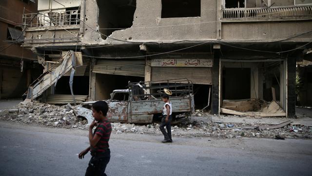 Children walk near damaged buildings in rebel-held Ain Tarma eastern Damascus suburb of Ghouta Syria