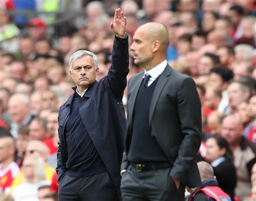 Manchester United manager Jose Mourinho left and Manchester City manager Pep Guardiola watch from the touchline during the English Premier League soccer match between Manchester United and Manchester City at Old Trafford Manchester England Saturday