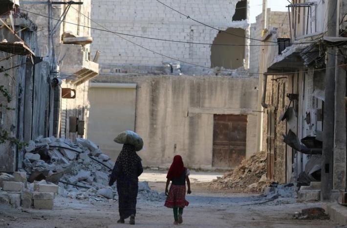 Civilians walk past damaged buildings in the rebel-held al Sheikh Said neighbourhood of Aleppo Syria