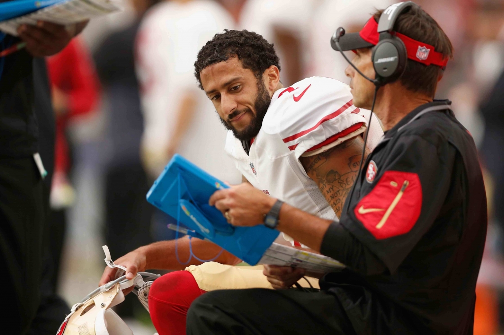 GLENDALE AZ- SEPTEMBER 27 Quarterback Colin Kaepernick #7 of the San Francisco 49ers looks at a playbook on the sidelines during the NFL game against the Arizona Cardinals at the University of Phoenix Stadium