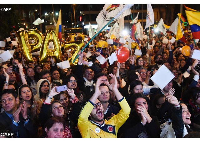 Colombians celebrate as they watch on a giant screen the peace accord being signed in Havana Cuba.- AFP