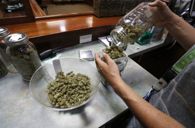 An employee places marijuana for sale into glass containers at The Station a retail and medical cannabis dispensary in Boulder Colo. Thursday Aug. 11 2016. The DEA announced Thursday Aug. 11 2016 that the Obama administration will keep marijuana