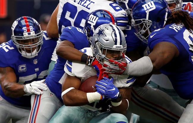 Dallas Cowboys running back Ezekiel Elliott is wrapped up by New York Giants defenders after a short run in the first half of an NFL football game Sunday Sept. 11 2016 in Arlington Texas