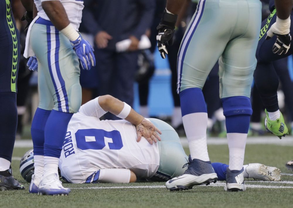 Dallas Cowboys quarterback Tony Romo holds his back after he was tackled during a preseason NFL football game against the Seattle Seahawks Thursday Aug. 25 2016 in Seattle. Romo left the game after the play