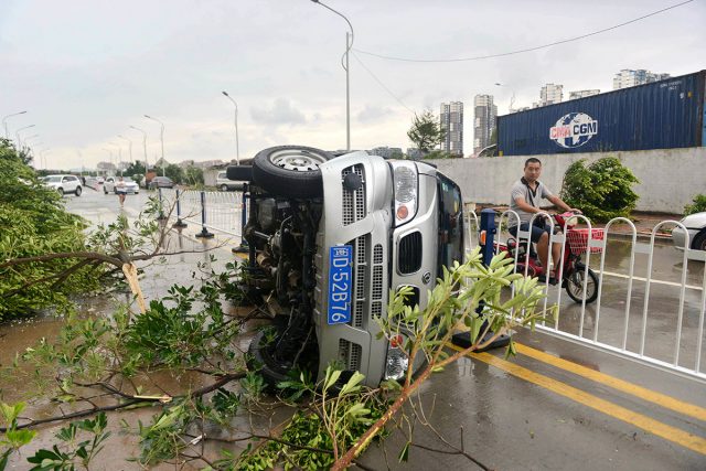 A man rides a scooter past an overturned vehicle and fallen trees in the wake of Typhoon Meranti in southeastern China's Fujian province. Chinatopix via AP