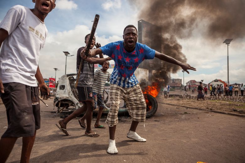 Demonstrators gather in front of a burning car during an opposition rally in Kinshasa