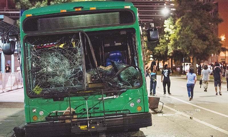 Demonstrators walk away from a damaged bus in downtown Charlotte.—AFP