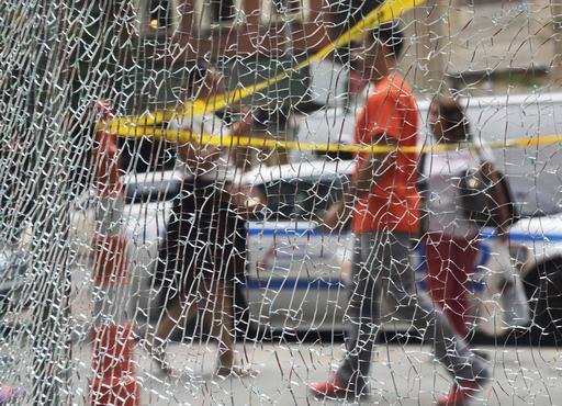 New Yorkers pass a shattered storefront window on W. 23rd St. in Manhattan Tuesday Sept. 20 2016 in New York. The window was hit by shrapnel from the terrorist bomb that exploded across the street Saturday evening. An Afghan immigrant wanted in the