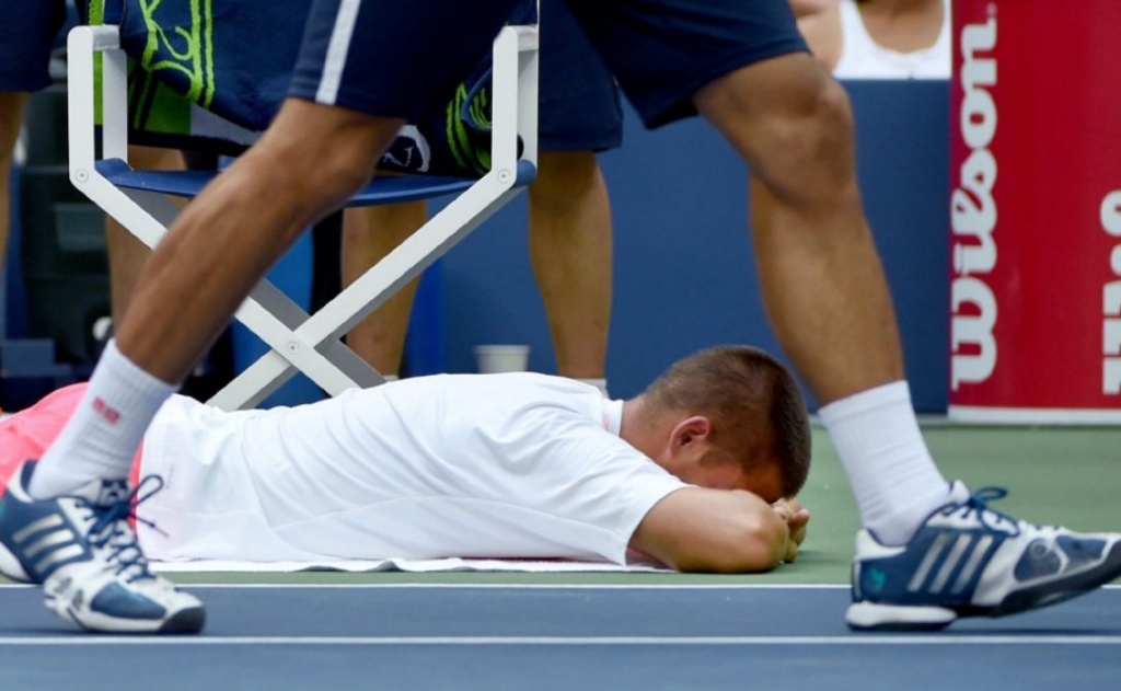 Novak Djokovic walks by Russia's Mikhail Youzhny while the latter gets treament during a medical timeout. Youzhny retired with a strained hamstring during the first set