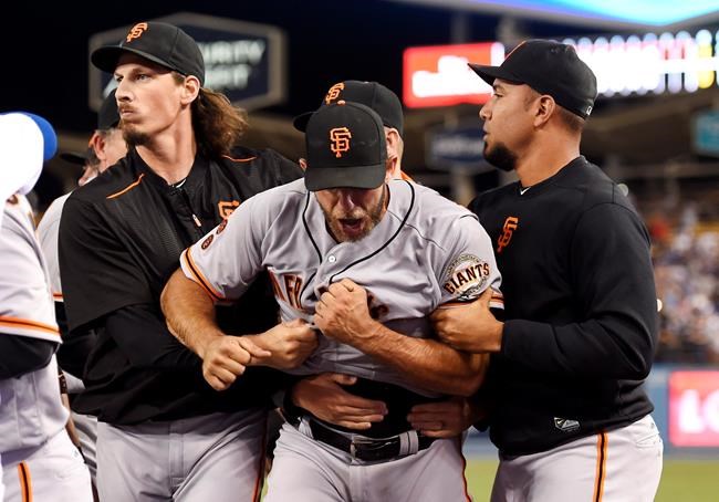 San Francisco Giants starting pitcher Madison Bumgarner center yells as he is pulled away by teammates after he and Los Angeles Dodgers&#39 Yasiel Puig got into a scuffle that emptied both benches after Puig was thrown out at first by Bumgarner during