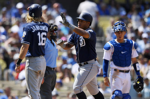 San Diego Padres Yangervis Solarte center is congratulated by Travis Jankowski left after hitting a two-run home run as Los Angeles Dodgers catcher Austin Barnes watches during the third inning of a baseball game Sunday Sept. 4 2016 in Los Angele