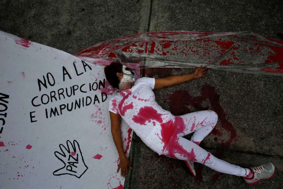 A protestor stained with fake blood lies beside a sheet marked with slogans protesting corruption and impunity as well as government repression outside the offices of congress in Mexico City Thursday Sept. 1 2016. When President Enrique Pena Nieto del