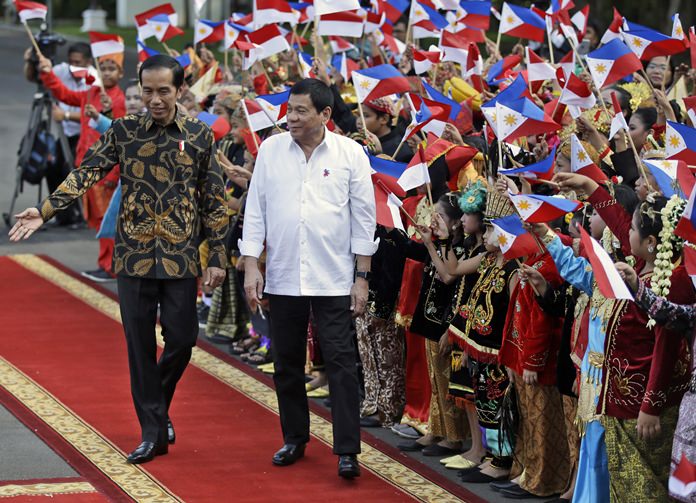 Philippine President Rodrigo Duterte right walks with his Indonesian counterpart Joko Widodo as school children in traditional dress wave the national flags of the two countries during a welcome ceremony at Merdeka Palace in Jakarta Indonesia Friday