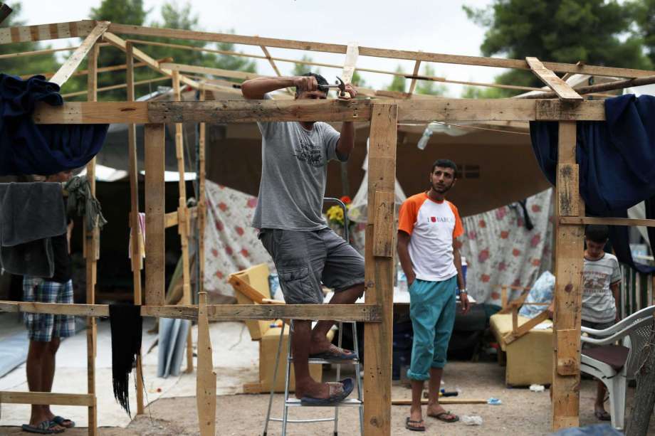 A Syrian man hammers a nail on woods as he prepares his family tent for winter at Ritsona refugee camp north of Athens which hosts about 600 refugees and migrants on Thursday Sept. 8 2016. The refugee crisis is expected to be a central issue in discuss