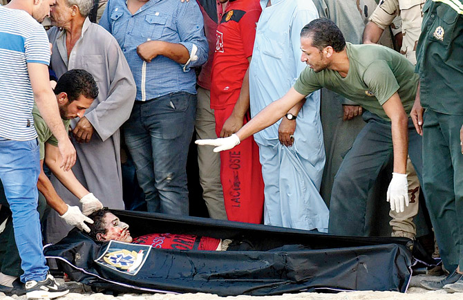 Egyptian policemen and medics stand over a body of a migrant along the shore in the Egyptian port city of Rosetta. Pic  AFP