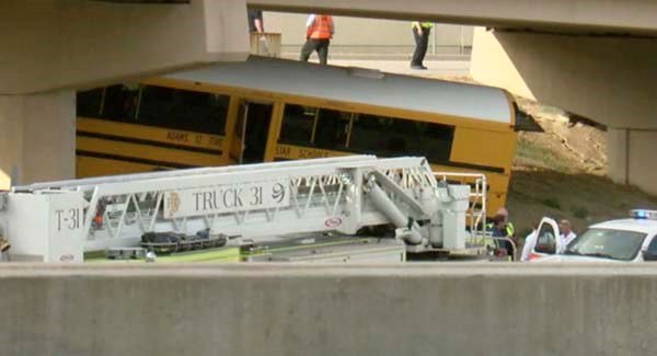 Emergency personnel stand near the the school bus that crashed into a concrete pillar in Denver yesterday. Pic AP