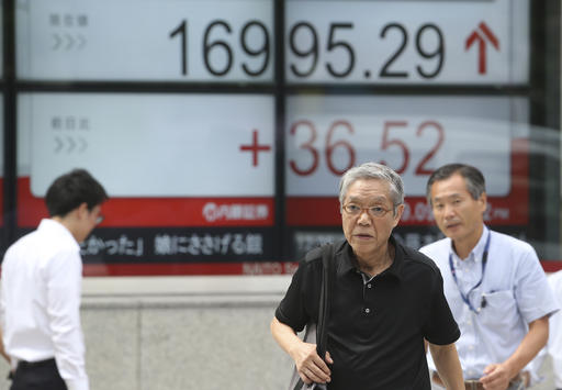 People walk by an electronic stock board of a securities firm in Tokyo Friday Sept. 9 2016. Asian markets were mostly lower Friday on disappointment about the European Central Bank's decision to keep policy unchanged