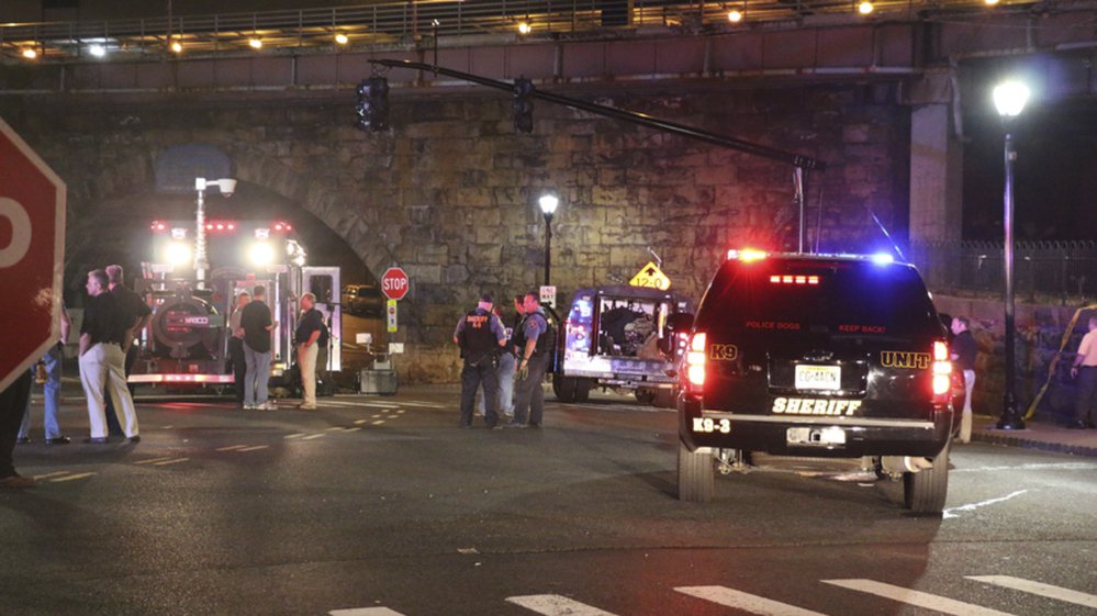 Bomb squad personnel stand around the scene of an explosion near the train station early Monday Sept 19 2016 in Elizabeth New Jersey. A suspicious device found Sunday night in a trash can near a New Jersey train station exploded early Monday as a bom