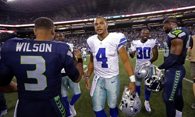 Dallas Cowboys quarterback Dak Prescott talks with Seattle Seahawks quarterback Russell Wilson and other players after a preseason NFL football game Thursday Aug. 25 2016 in Seattle. The Seahawks won 27-17