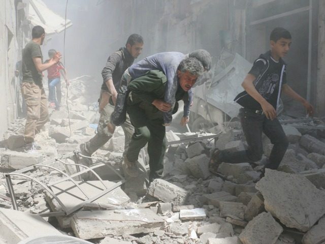 Syrians evacuate an injured man amid the rubble of destroyed buildings following a reported air strike on the rebel-held neighbourhood of Al-Qatarji in the northern Syrian city of Aleppo