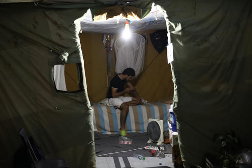 Sept. 13 2016 a Syrian man looks at his mobile phone inside his tent at Ritsona refugee camp north of Athens. Most of the people at the camp arrived in Greece in March crossing to Lesbo