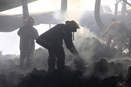 Firefighters sift through the rubble of a burned garments factory in Bangldesh