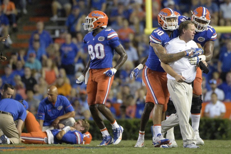 Florida coach Jim Mc Elwain is restrained by tight end De Andre Goolsby and offensive lineman Fred Johnson after Mc Elwain showed his displeasure after quarterback Luke Del Rio left was knocked out of the game during the second half of an NCAA