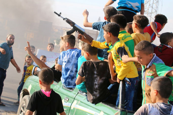 A boy carries a toy gun while riding a pick-up truck with other boys during a demonstration calling for aid to reach Aleppo near Castello road in Aleppo Syria. — Reuters