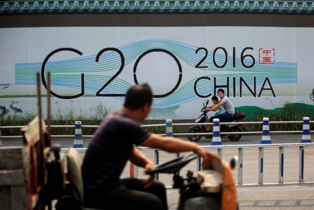 People cycle past a billboard for the G20 summit in Hangzhou Zhejiang province China